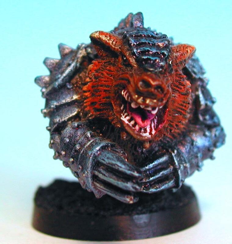 Painted monster miniature with spiky armor and a snarling red face on a black base.