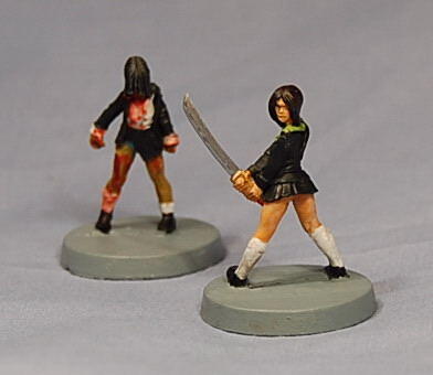 Two painted miniature female figures on round bases, one holding a sword.