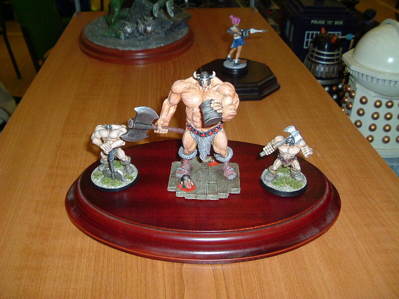 Photograph of painted fantasy miniatures on a polished red oval display base.