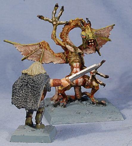 Painted fantasy miniatures: cloaked figure facing a dragon on bases.