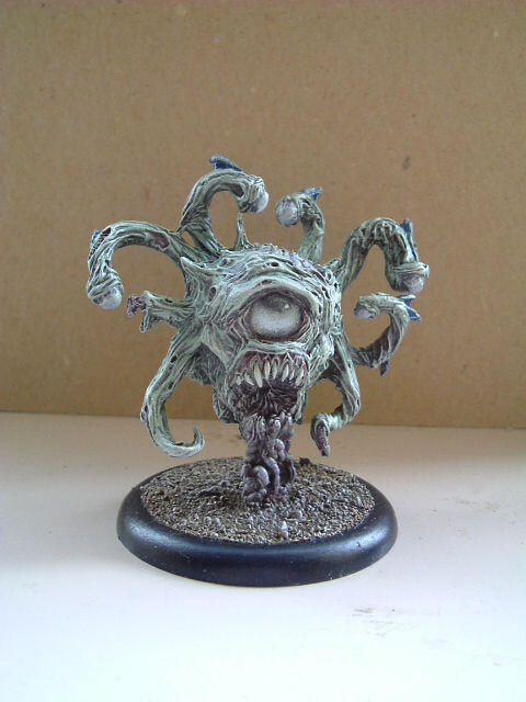 Painted miniature of a tentacled monster on a round base against a plain background.