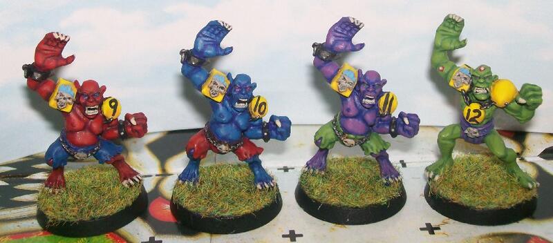 Four colorful fantasy miniature figures on grassy bases.