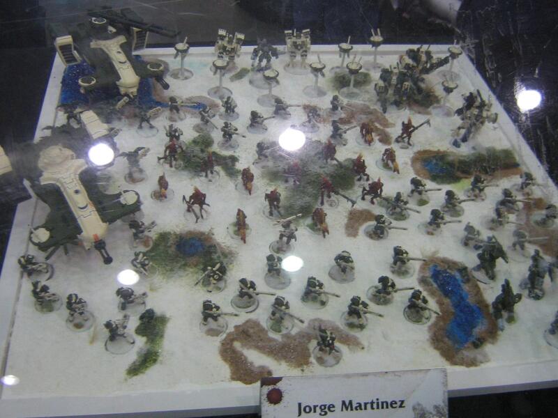 Tabletop display of painted miniature soldiers and scenery under bright lights.