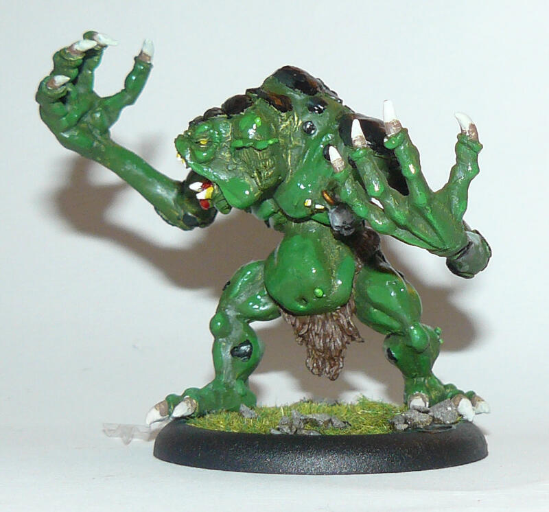 Photo of a painted green monster miniature on a black base, posed with raised claws.