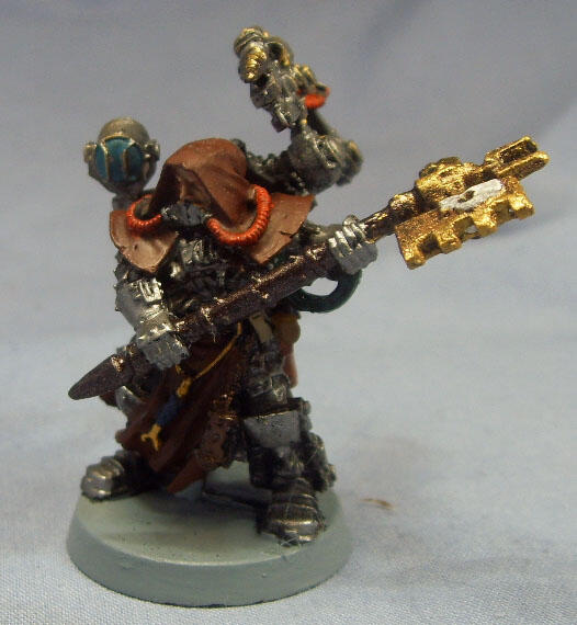 Painted miniature of an armored warrior aiming a gold gun, one arm raised.