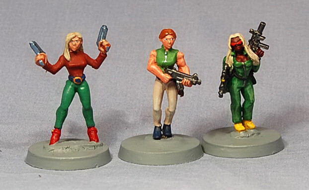 Three painted miniature adventurer figures on gray bases against a gray background.